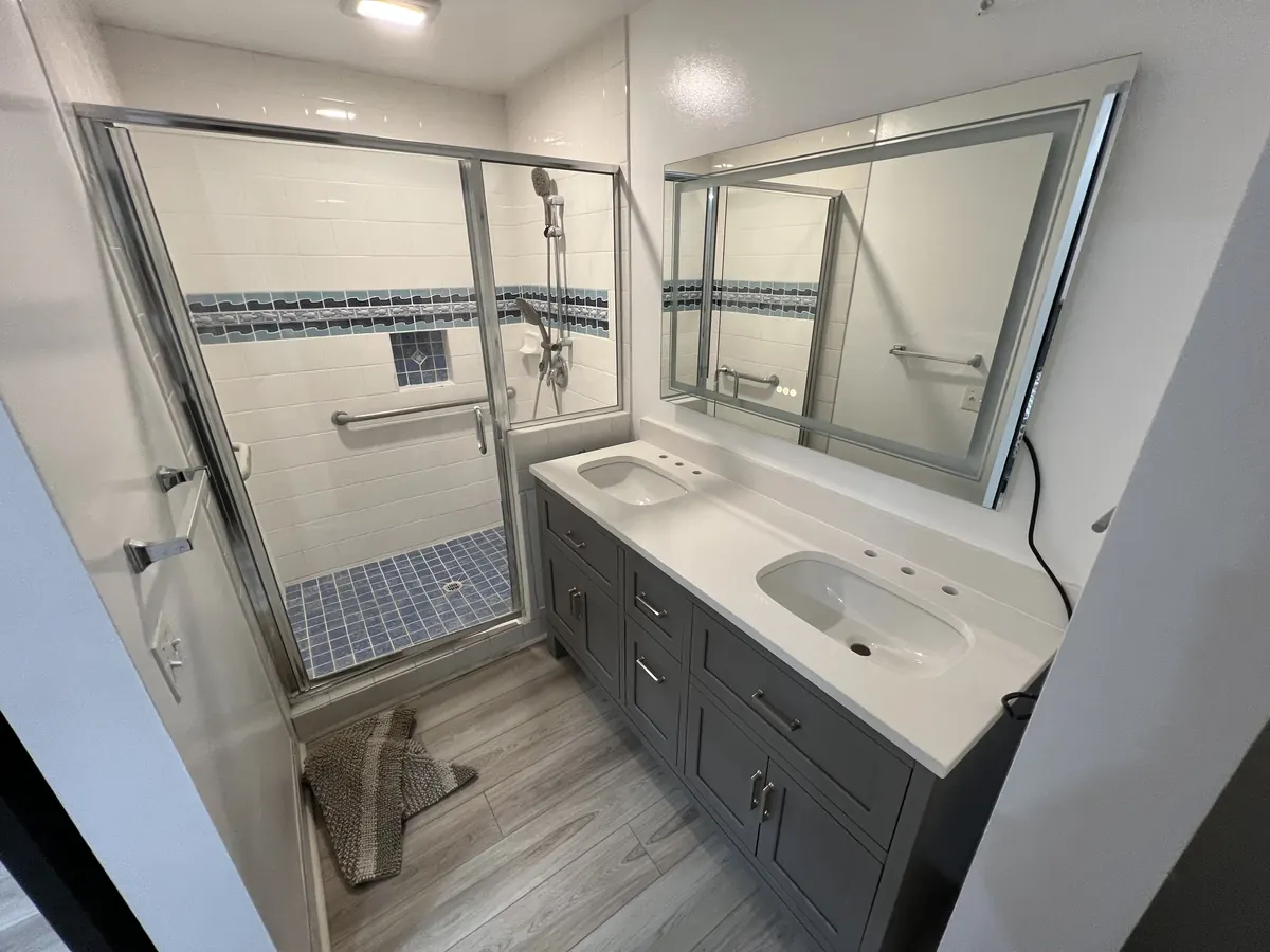 Bathroom with a new double vanity, framed mirror and glass shower door