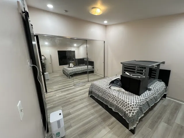 Bedroom after the refresh, with gray wood-look vinyl plank and mirrored closet doors
