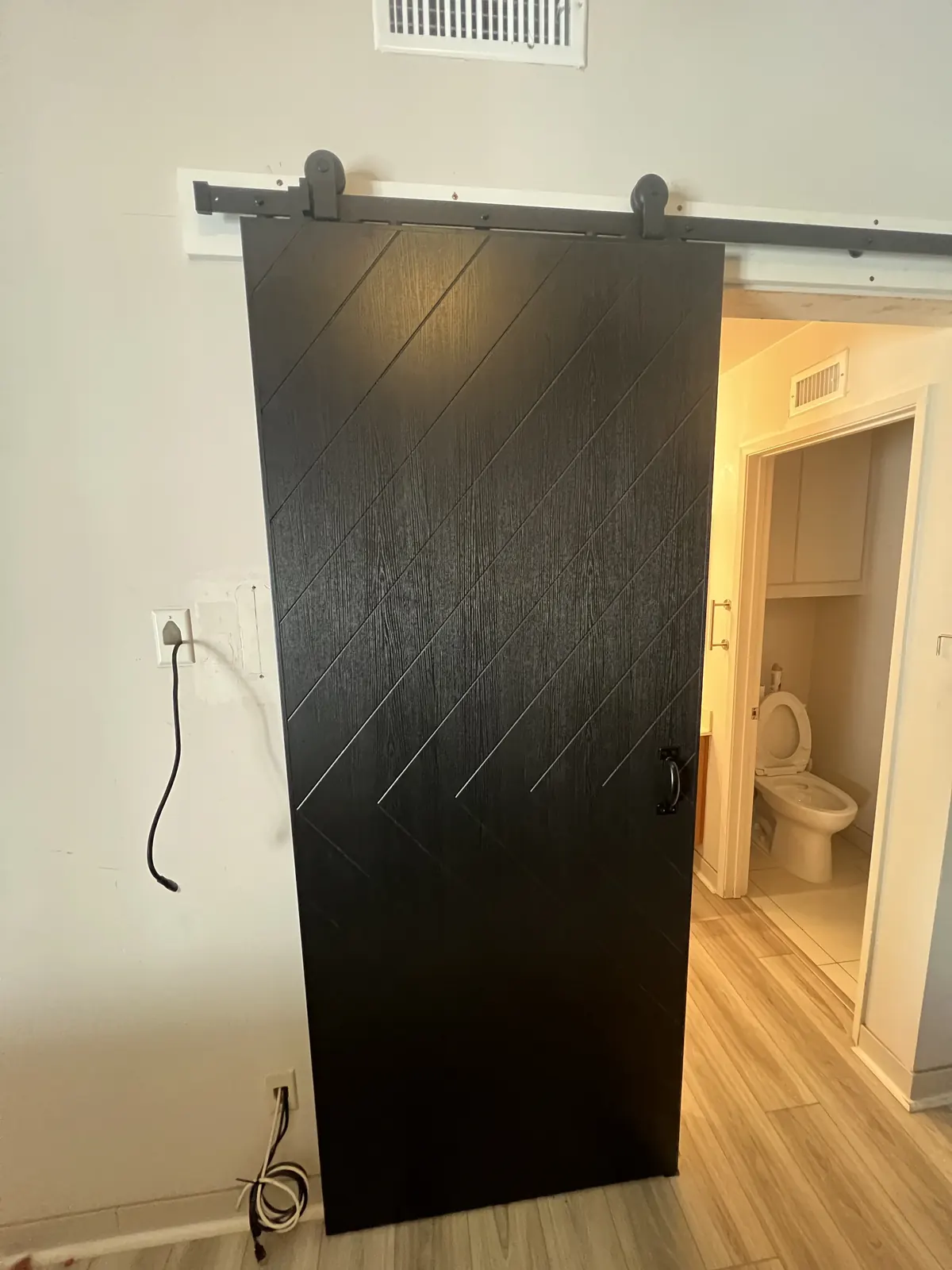 Black barn door on a sliding track closing off a bathroom