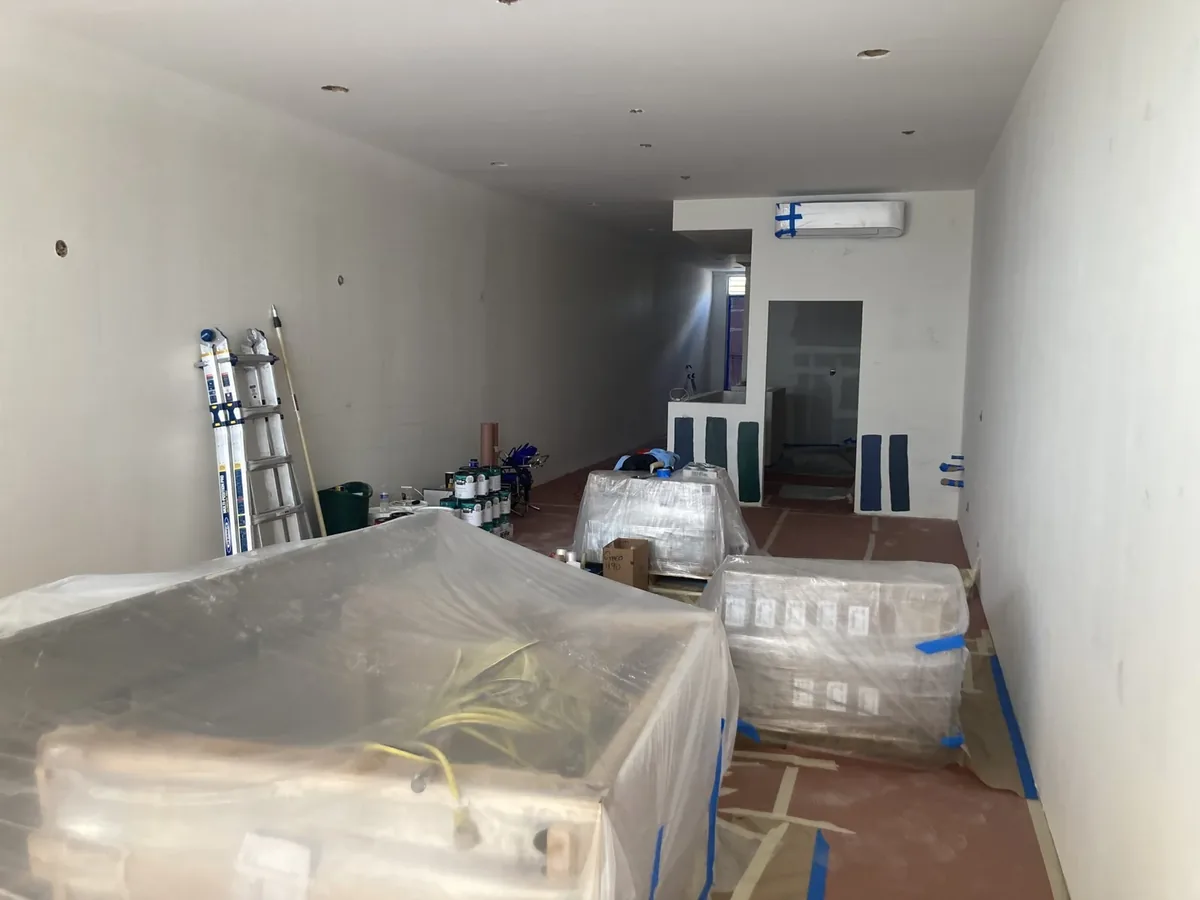 Commercial interior under renovation in San Diego, with protected floors and exposed ceiling services