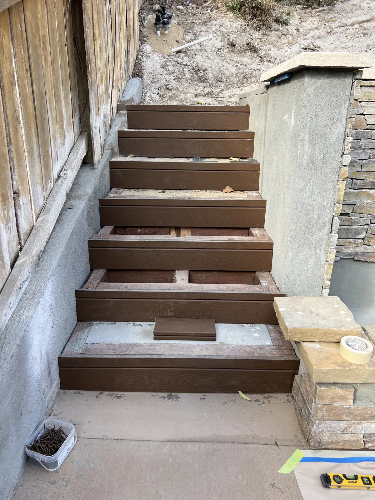 Composite steps being finished beside a stone veneer pillar