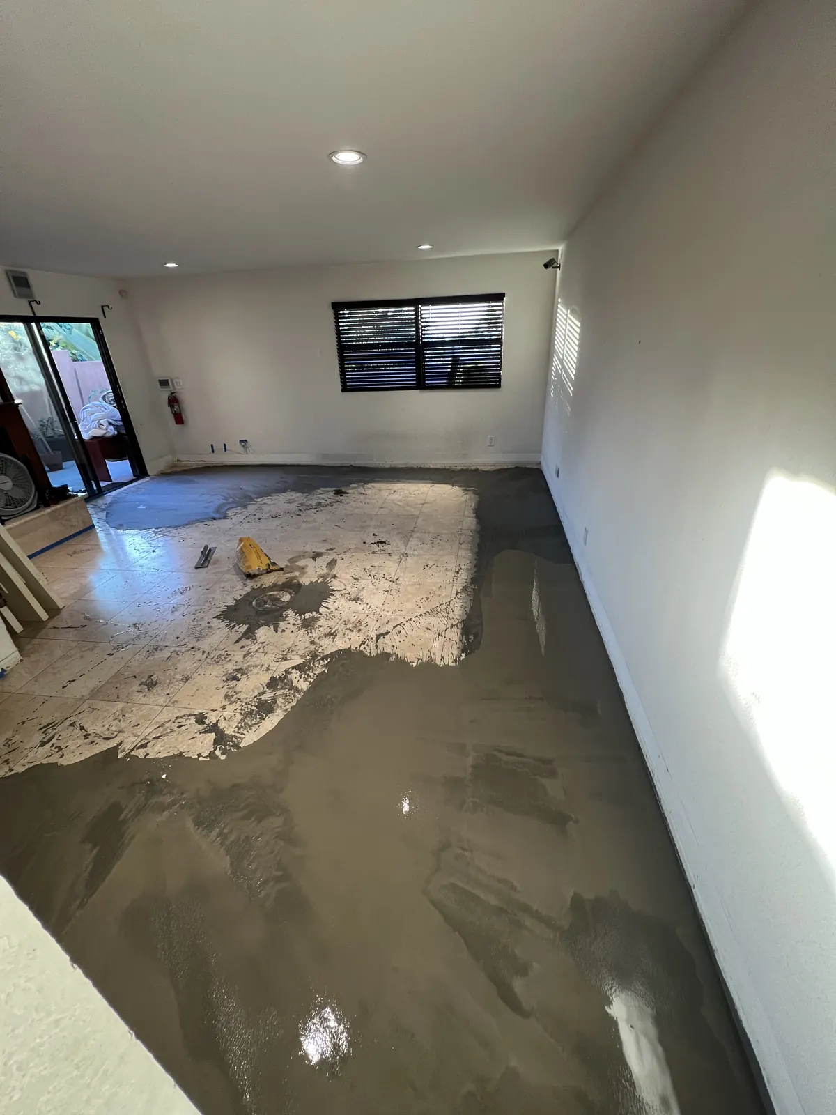Self-leveling compound poured across a room to flatten the subfloor before new flooring