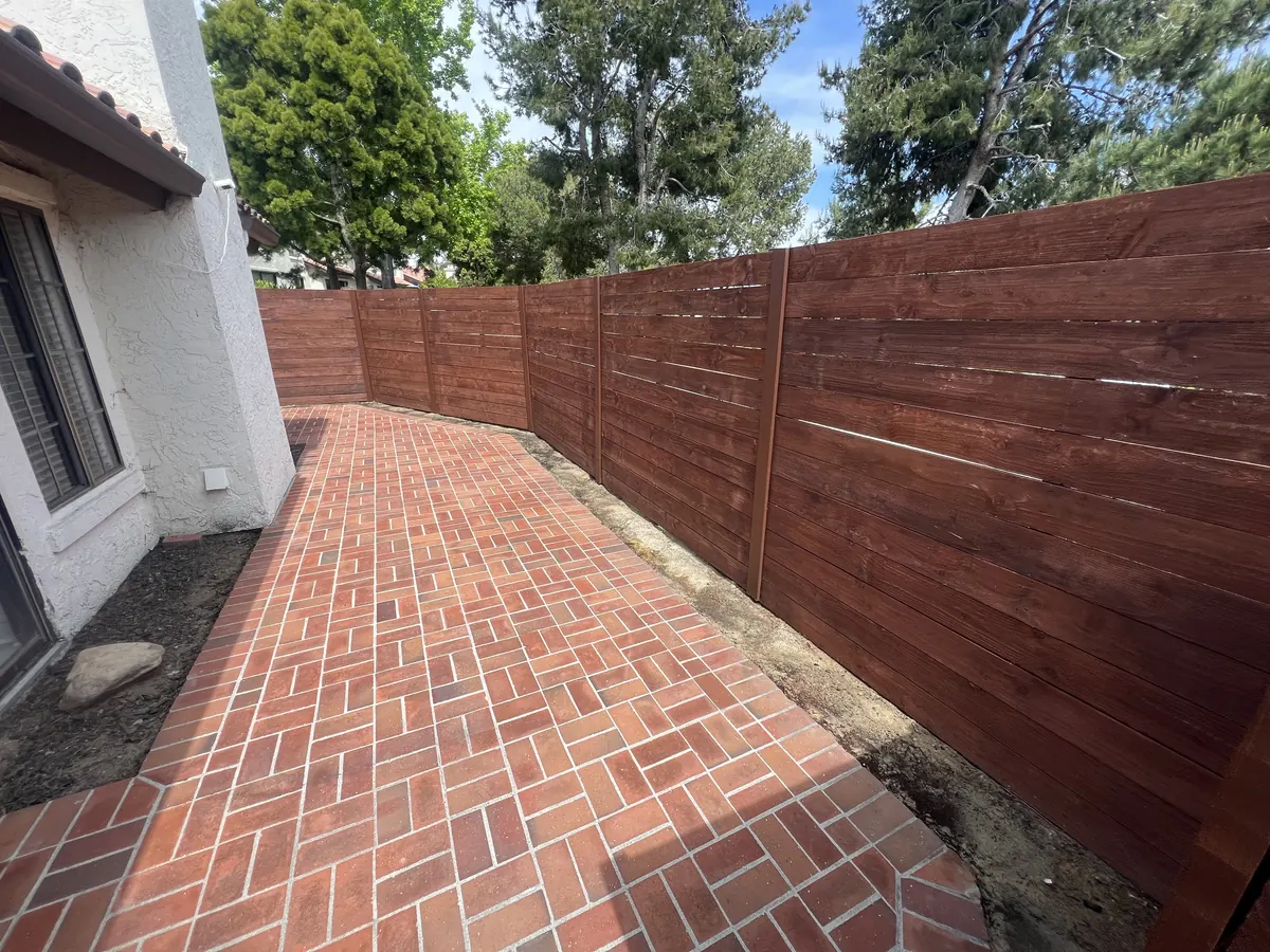 New horizontal wood fence along a side yard with a brick walkway