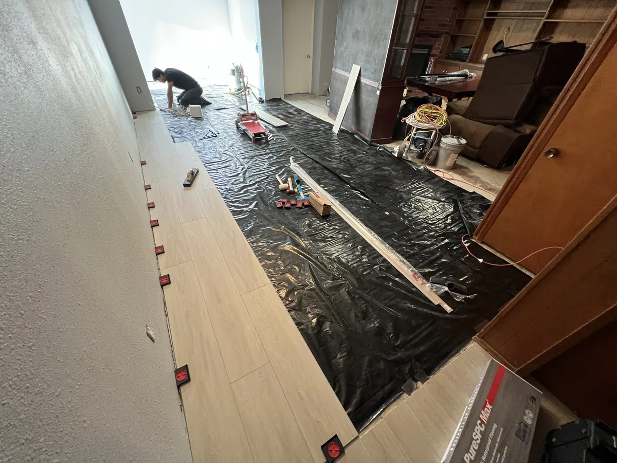 Rigid vinyl plank being installed over plastic sheeting on a concrete slab