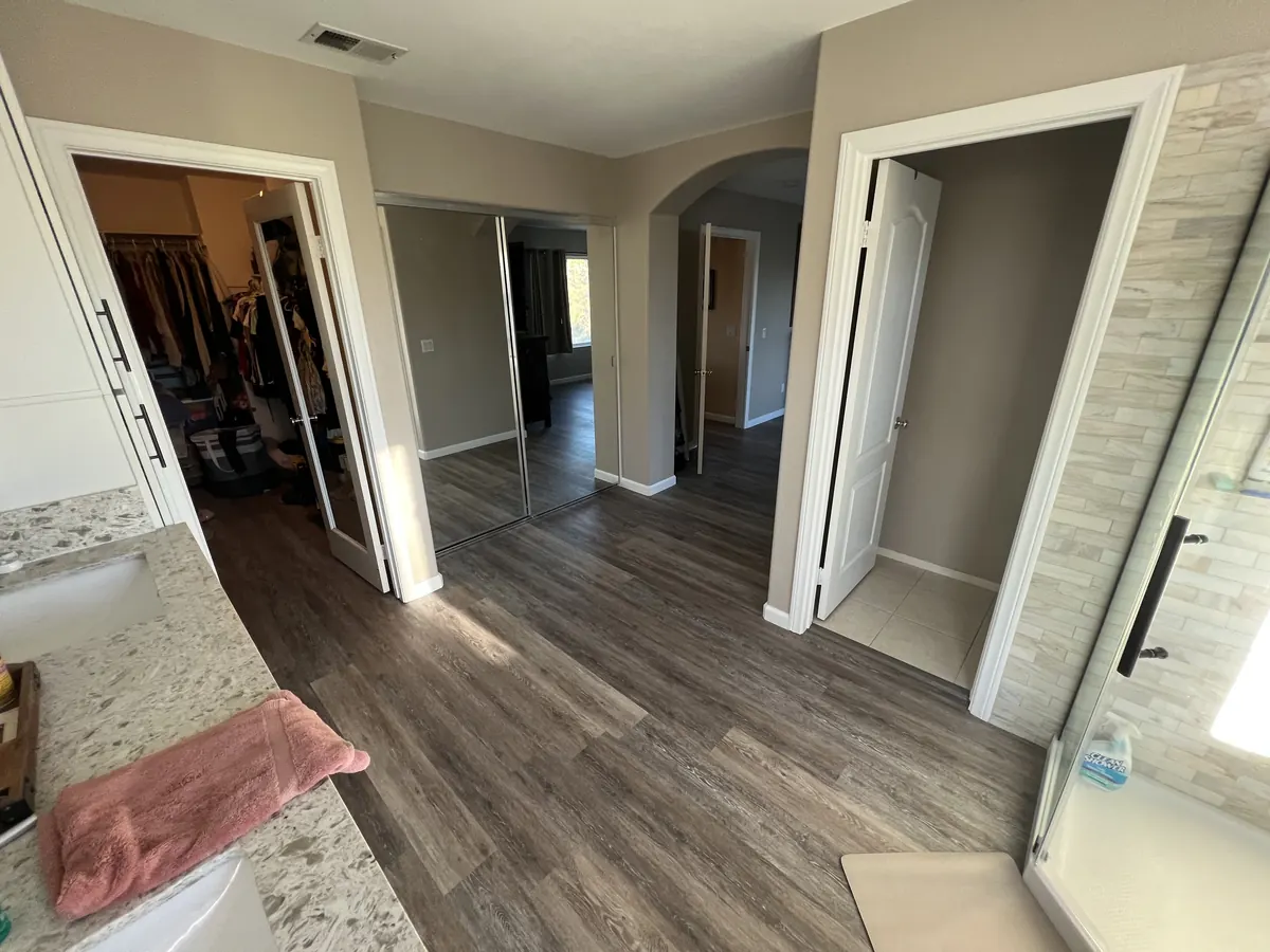 Primary suite with new gray wood-look vinyl plank running from the bathroom to the closets