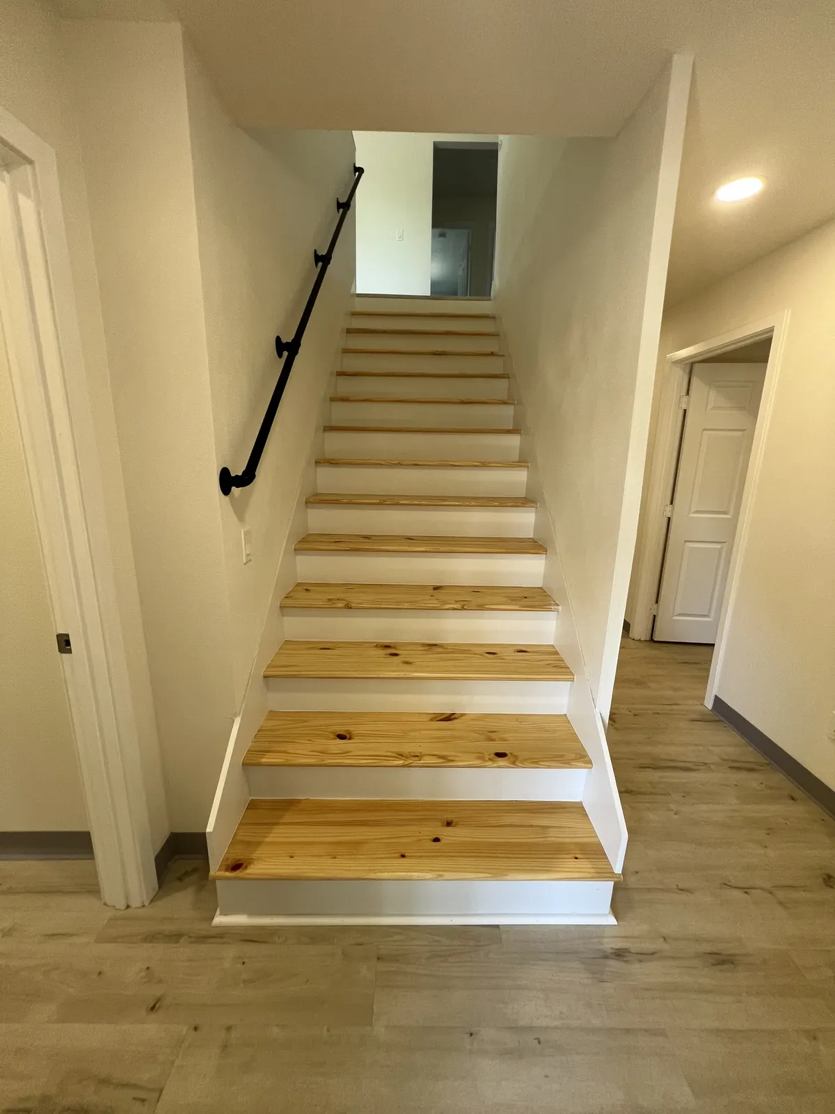 Rebuilt staircase with natural wood treads, white risers and a black metal handrail