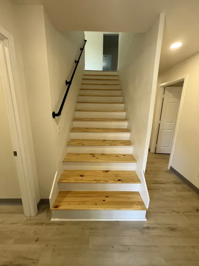 Rebuilt staircase with natural wood treads, white risers and a black metal handrail