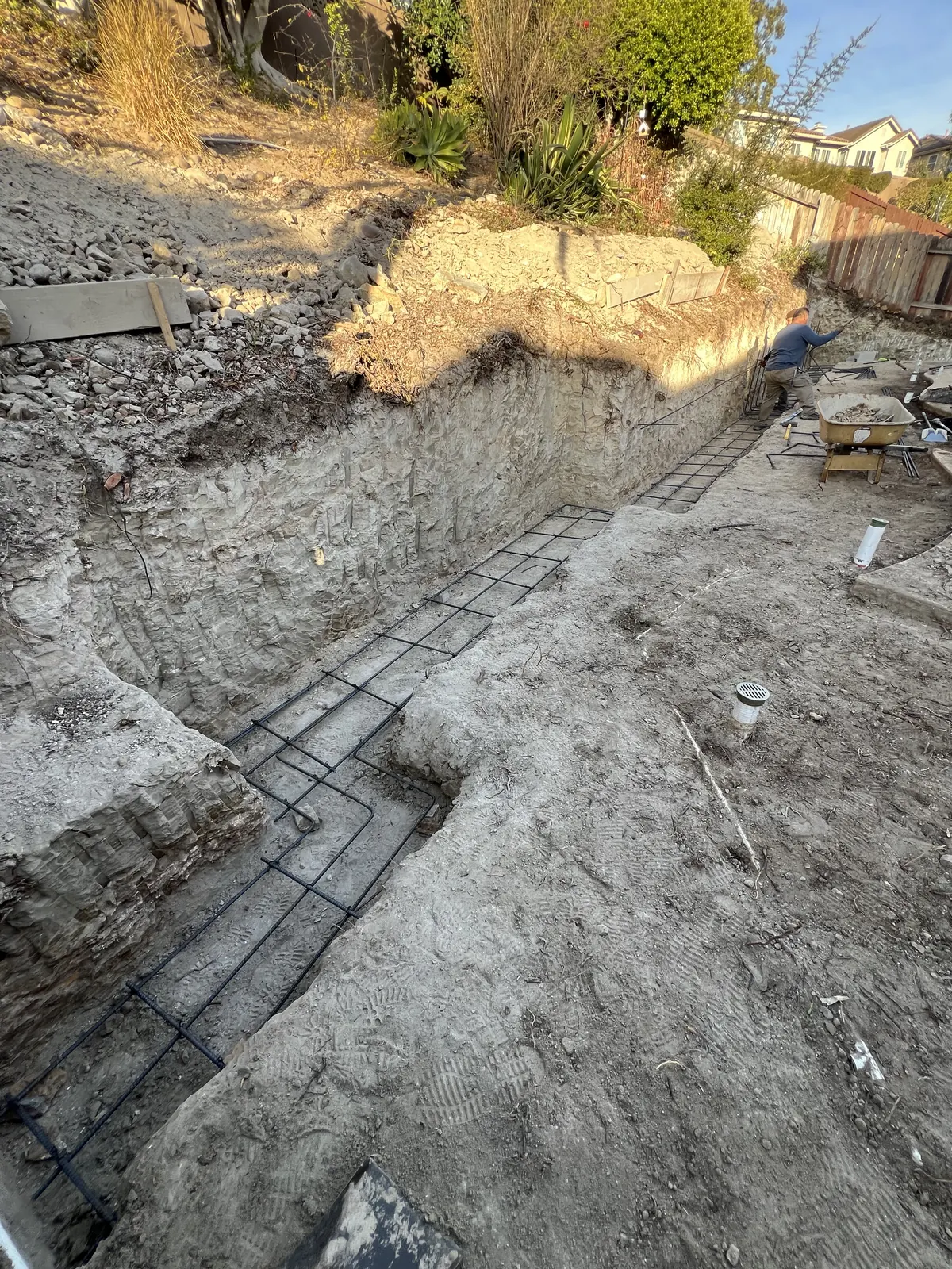 Excavated footing with rebar laid for a new retaining wall along the backyard slope