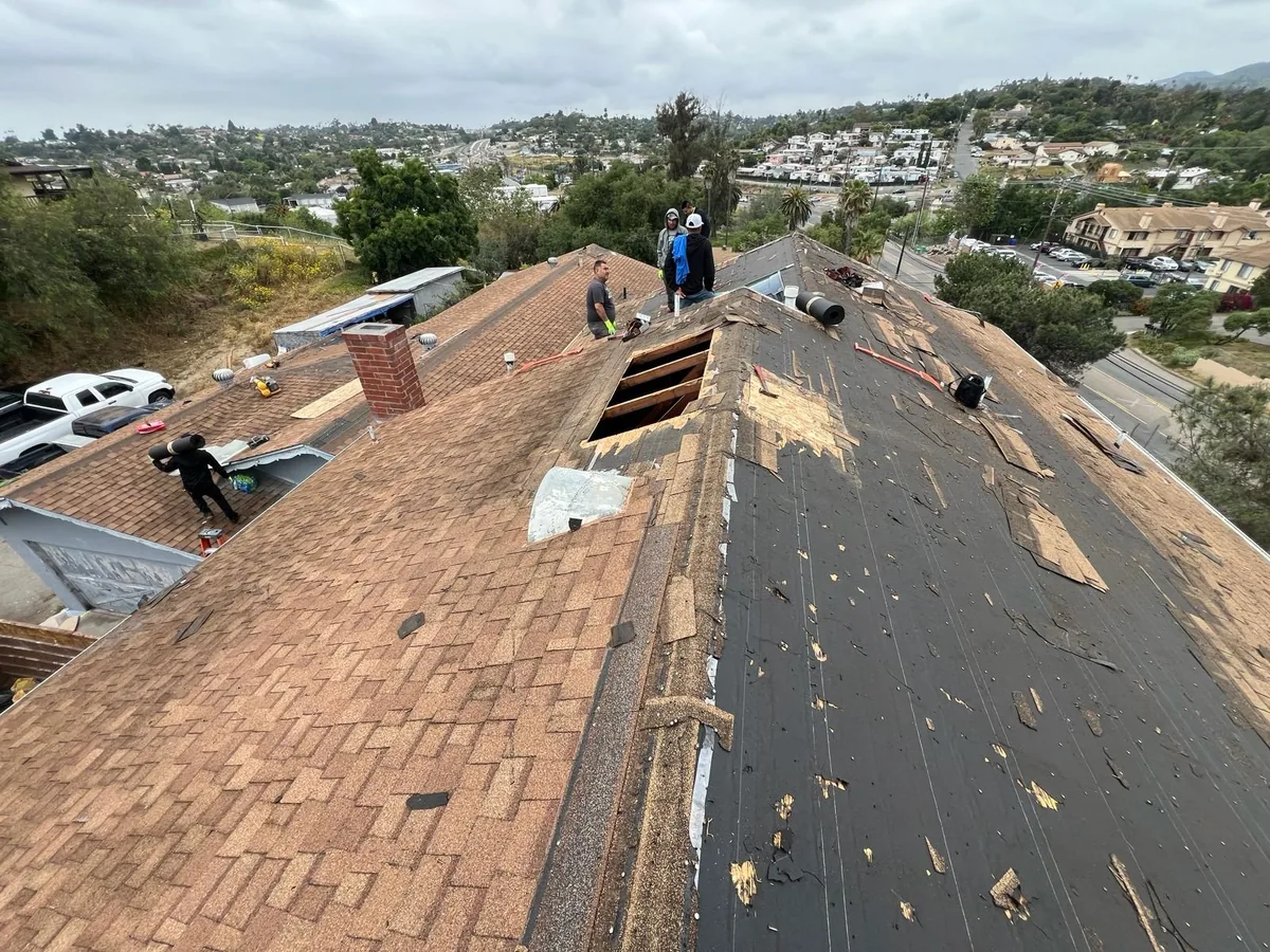 Roofing crew working on a sloped residential roof in San Diego during a shingle replacement