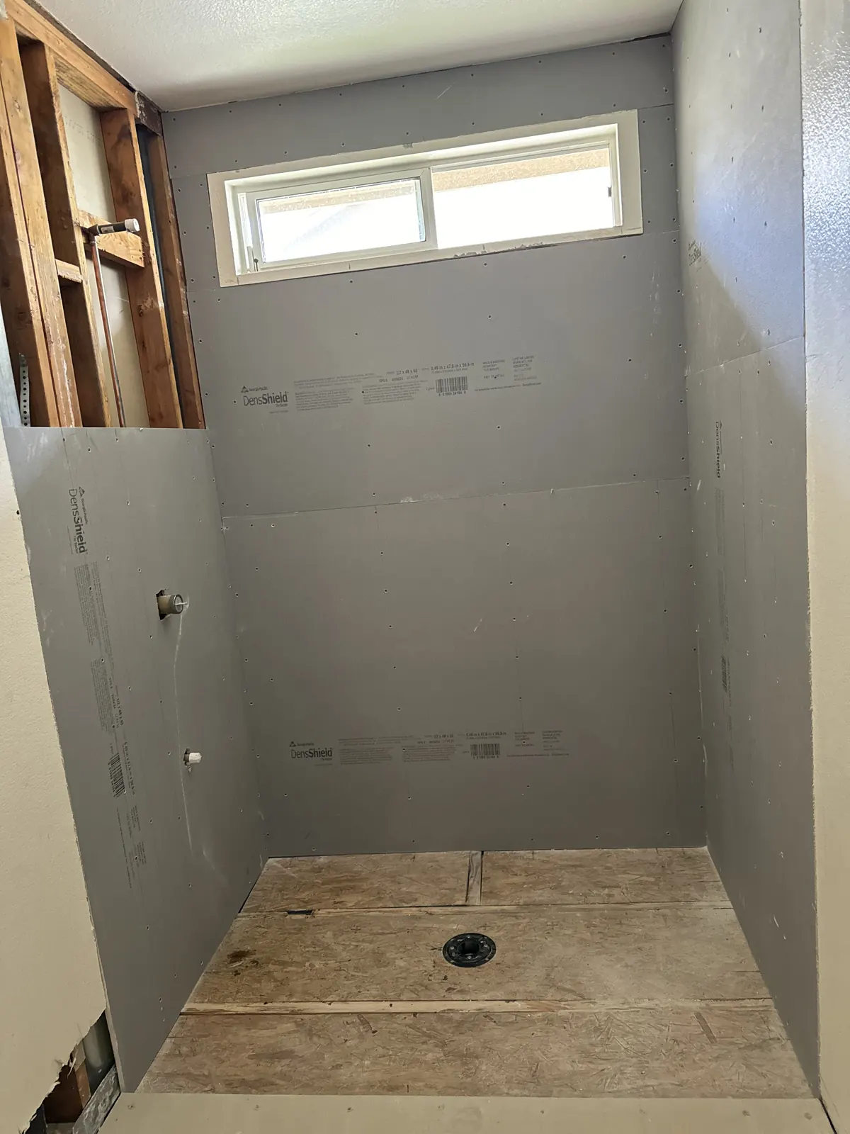 Gray tile backer board on the shower walls around the window, before tile