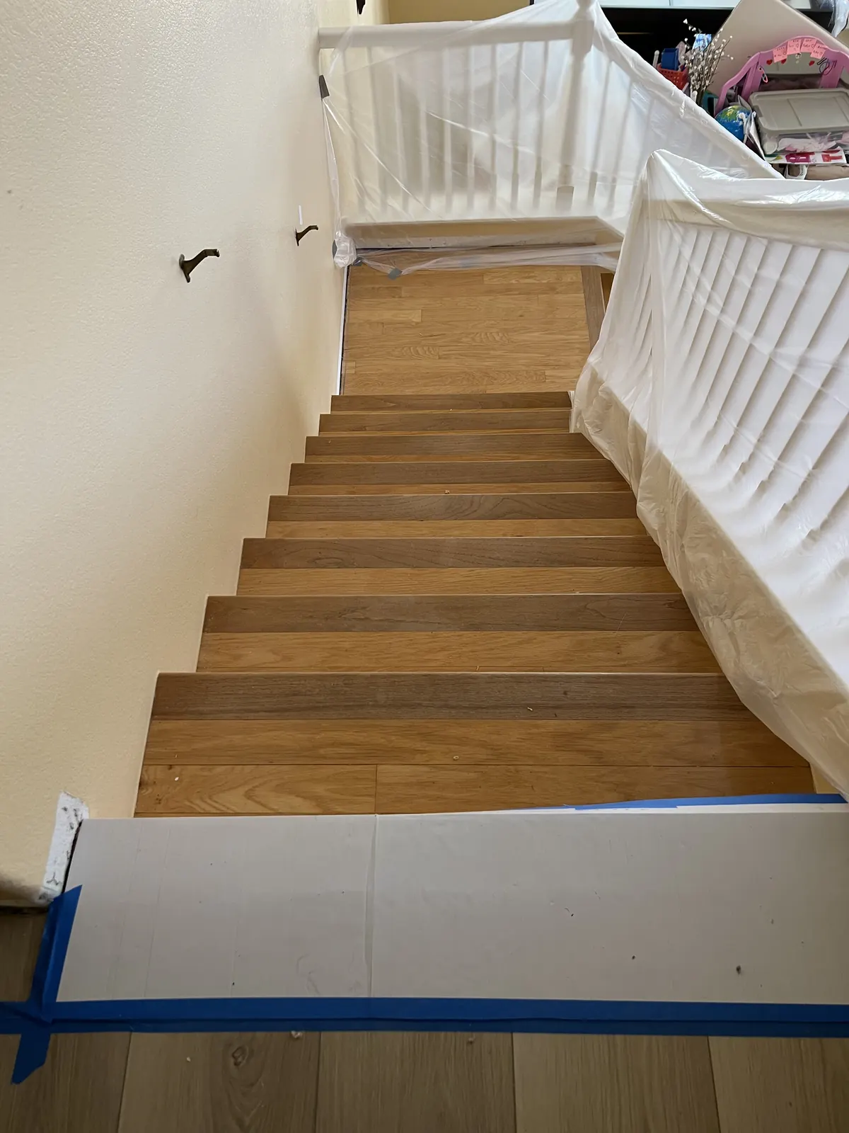 Staircase with new wood-look treads, the white balusters protected during the work