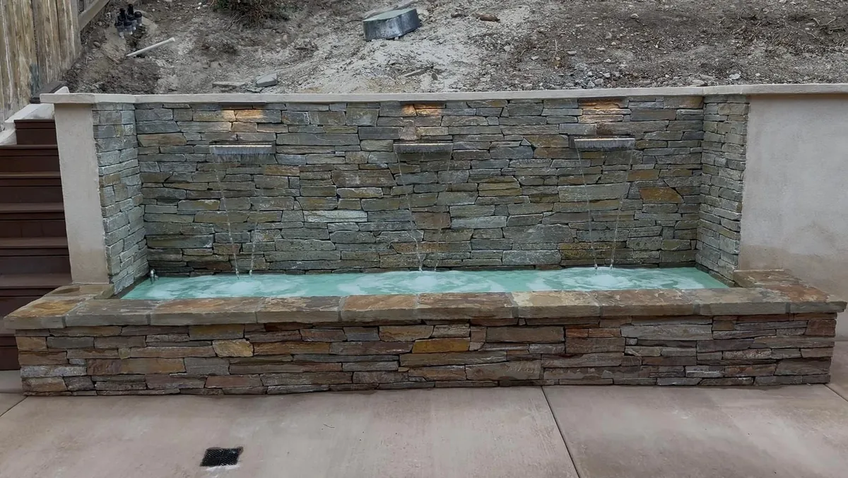 Stone water feature with three spouts in a finished San Diego outdoor living space