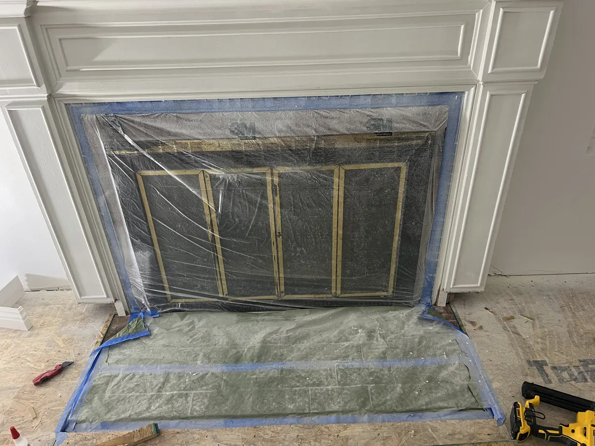 New white fireplace surround with paneled trim, the firebox masked for the finishing work