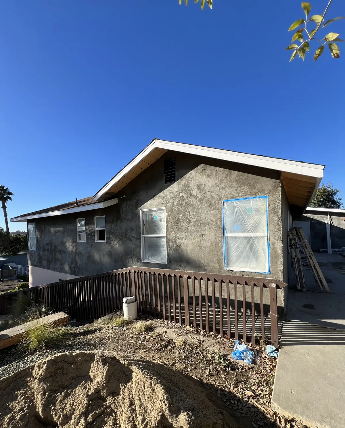 House after the new stucco went on, windows still masked and the deck railing in place