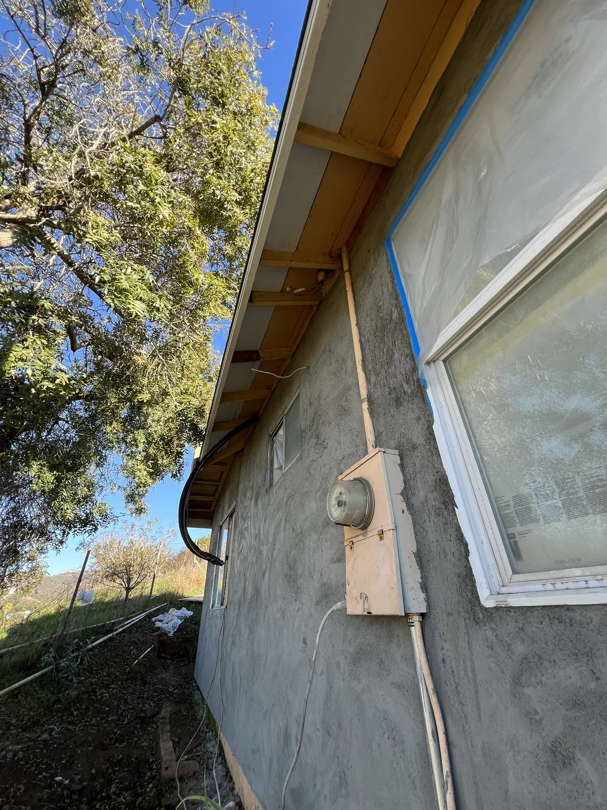 Fresh stucco coat on the side wall of the house, windows masked during the exterior work